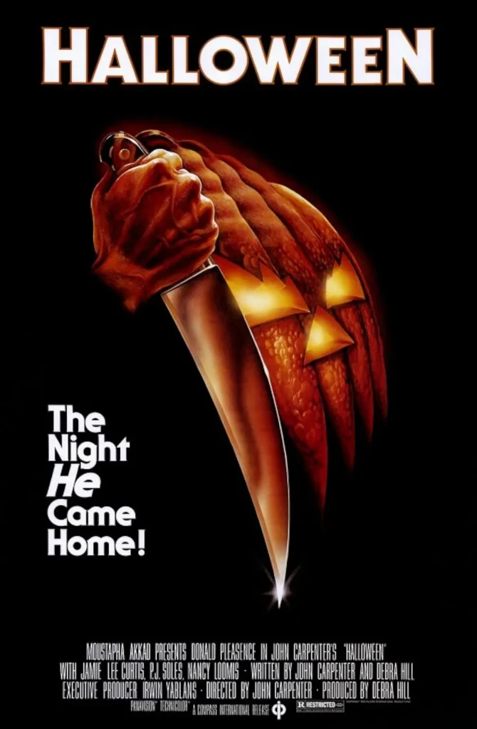 Poster for Halloween 1978, featuring a hand gripping a knife that transitions into a jack-o’-lantern face, alongside the tagline ‘The Night He Came Home.’