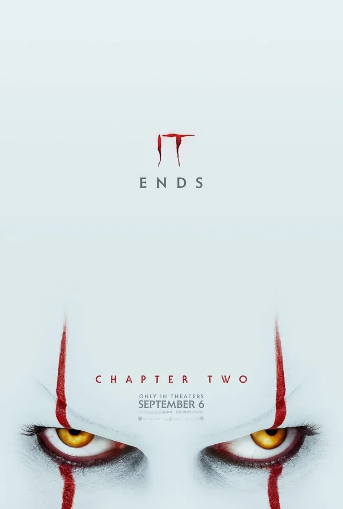 IT Chapter Two movie poster featuring a close-up of Pennywise’s sinister yellow eyes peering from the bottom, framed by his iconic red face paint. The tagline ‘IT ENDS’ looms above, creating an ominous and suspenseful atmosphere, emphasizing the film's climactic conclusion.